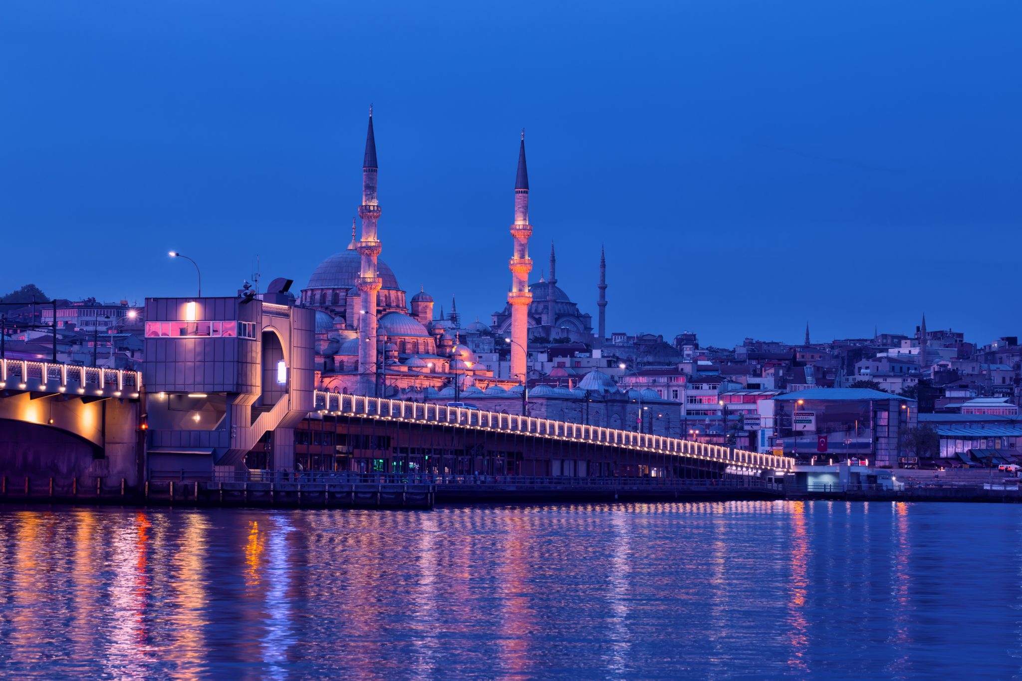 Galata Bridge and Yeni Cami Mosque in Istanbul at night. View from the embankment to the illuminated Galata Bridge and the New Mosque illuminated by electric lights. Istanbul, Turkey